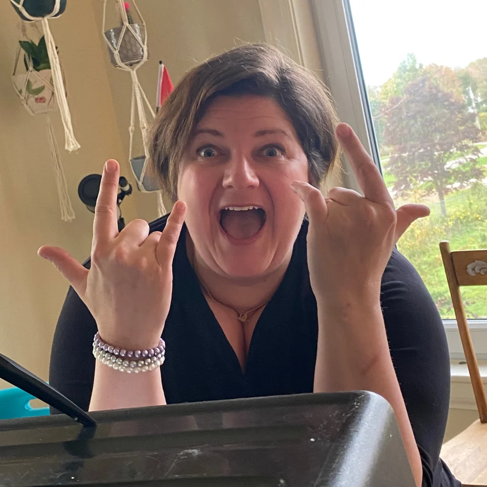 Audrey smiling and making a playful hand gesture at a table